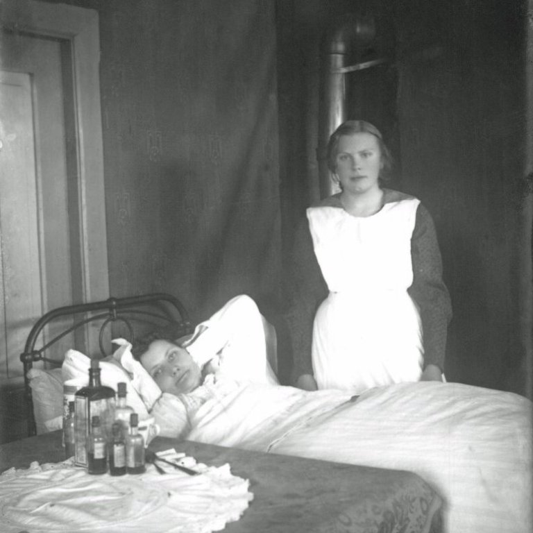 Valgerður Hallgrímsdóttir hjúkrunarkona (t.v.) á Húsavík, hjúkraði fólki í sjúkraskýlinu Vallholti og Læknishúsinu, einnig síðar á Sjúkrahúsinu eftir að það var byggt 1936. Myndin er úr Vallholti. Myndin tekin ca. 1898-1912.