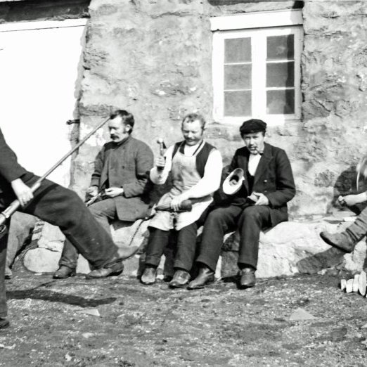 Vestan við Jaðar, eitt húsa K.Þ. Frá vinstri má kenna Rút Jónsson prest (með byssuna), þá Pétur Jónsson (síðar í Borgarhóli, rak skósmiðaverkstæði um hríð og Þorberg Númason skósmið (með svuntuna). Nokkrari skósmiðir störfuðu á Húsavík á fyrsta áratug aldarinnar.